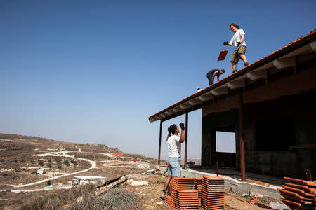 FILE PHOTO: Men work on the roof of a house under construction in the unauthorised Jewish settler outpost of Havat Gilad, south of the West Bank city of Nablus November 5, 2013. REUTERS/Nir Elias/File Photo
