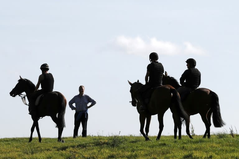 Racehorse trainer George Baker talks with riders on the gallops near his Robins Farm stables