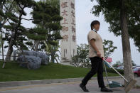 A cleaner walks by the Evergrande's name and logo at its new housing development in Beijing, Wednesday, Sept. 15, 2021. One of China's biggest real estate developers is struggling to avoid defaulting on billions of dollars of debt, prompting concern about the broader economic impact and protests by apartment buyers about delays in completing projects. Rating agencies say Evergrande Group appears likely to be unable to repay all of the 572 billion yuan ($89 billion) it owes banks and other bondholders. That might jolt financial markets, but analysts say Beijing is likely to step in to prevent wider damage. (AP Photo/Andy Wong)