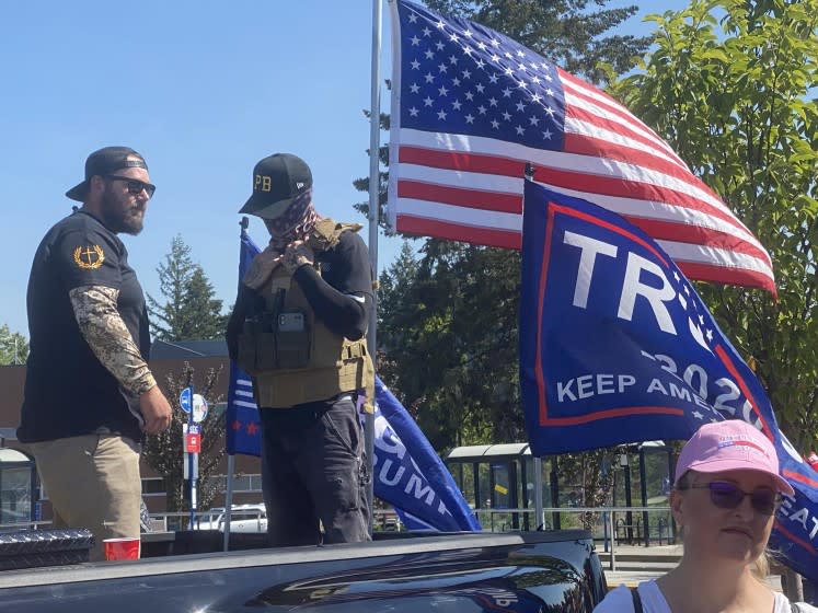 Men wearing symbols of Proud Boys, a right-wing extremist group, stand watch as supporters of President Donald Trump kick off a truck caravan near Portland Monday.