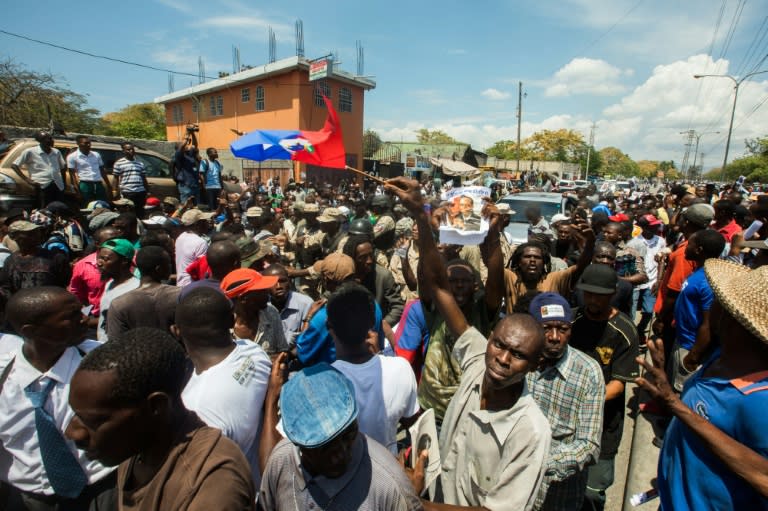 Crowds gather around the car of former Haitian President Jean-Bertrand Aristide, as he makes a rare public appearance to testify as a witness in a money laundering case