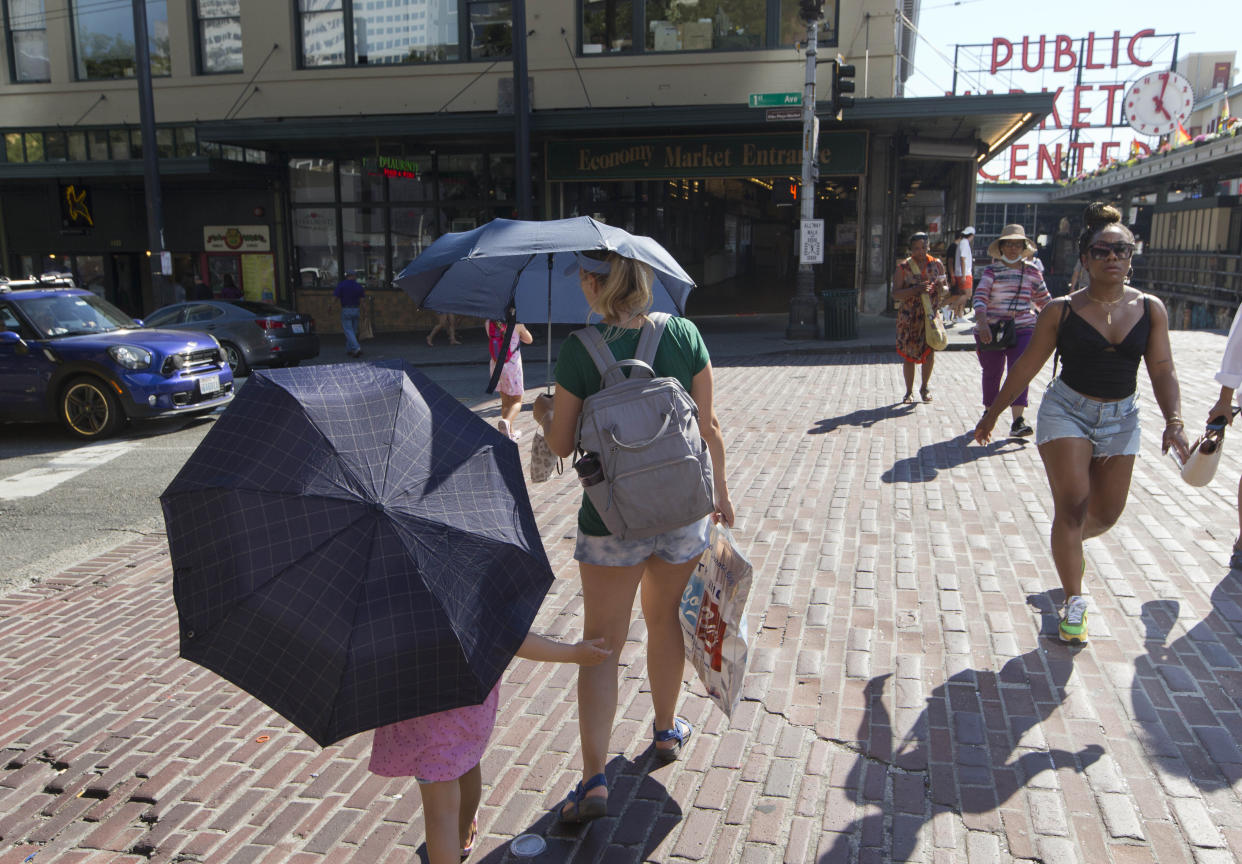 Sabina Ehmann and her daughter Vivian, visiting Seattle from North Carolina, are prepared with umbrellas to shield the sun during a heat wave hitting the Pacific Northwest, Sunday, June 27, 2021, in Seattle. Yesterday set a record high for the day with more record highs expected today and Monday. (AP Photo/John Froschauer)