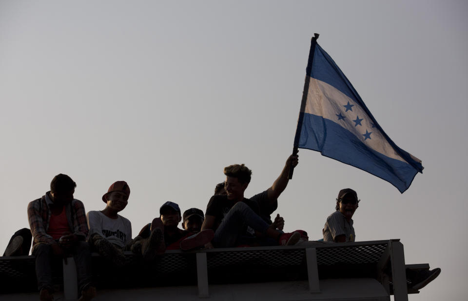 Honduran migrants flying their country's flag, ride atop a freight train during their journey toward the US-Mexico border, in Ixtepec, Oaxaca State, Mexico, Tuesday, April 23, 2019. The once large caravan of about 3,000 people was essentially broken up by an immigration raid on Monday, as migrants fled into the hills, took refuge at shelters and churches or hopped passing freight trains. (AP Photo/Moises Castillo)