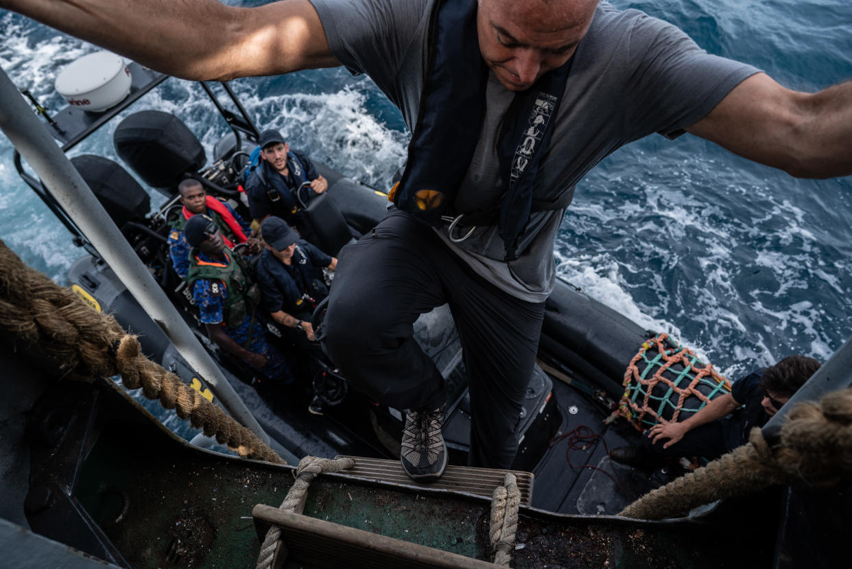 Ian climbs down into Sea Shepherd speedboat filled with Gambian Navy and fisheries officers. (Fábio Nascimento / The Outlaw Ocean Project)