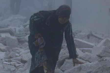 An injured woman walks at a site hit by an airstrike in the rebel-held al-Ansari neighbourhood of Aleppo, Syria December 7, 2016. REUTERS/Abdalrhman Ismail