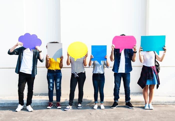 Six people hold paper speech bubbles in front of their faces.