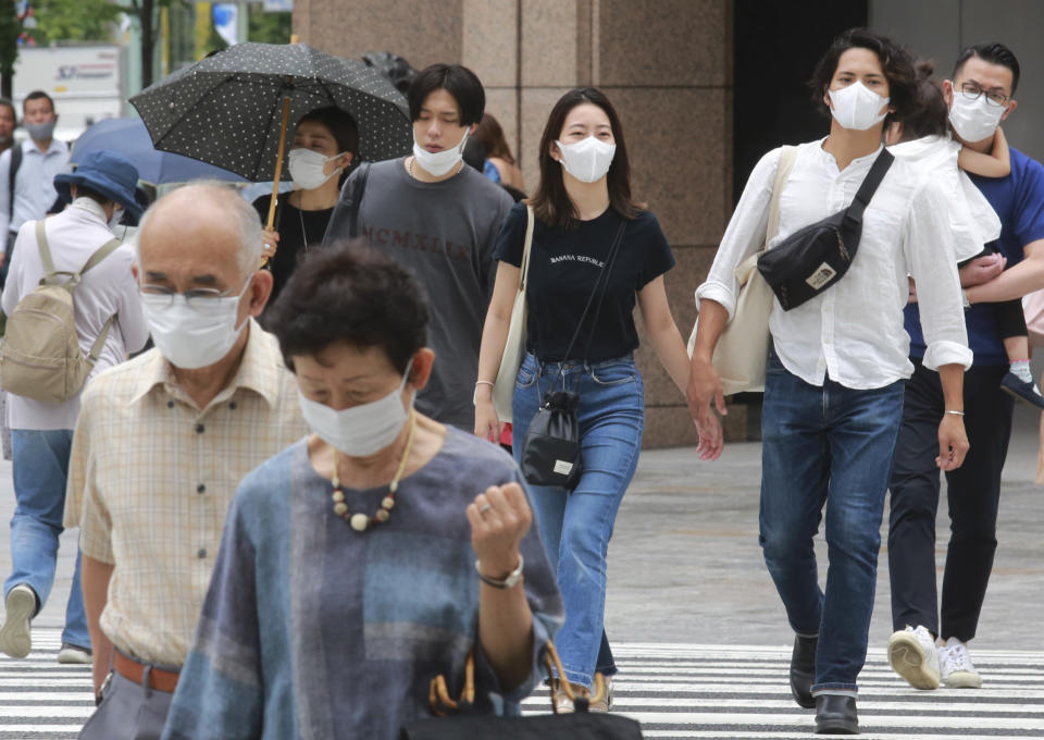 People wearing face masks to protect against the spread of the coronavirus walk on a street in Tokyo Tuesday, July 27, 2021. (AP Photo/Koji Sasahara)