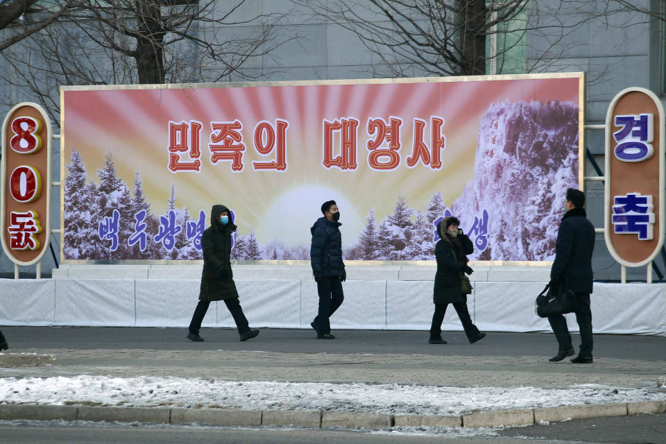 Citizens walk past a celebrative poster in Pyongyang, North Korea on the occasion of the 80th birth anniversary of the country's late leader Kim Jong Il, Wednesday, Feb. 16, 2022. The letters in the poster read " The great event of the nation. " (AP Photo/Cha Song Ho)