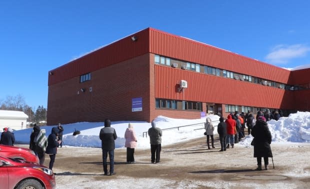 People wait in line outside Dr. Losier Middle School in Miramichi on Thursday for a COVID-19 mass testing clinic. 