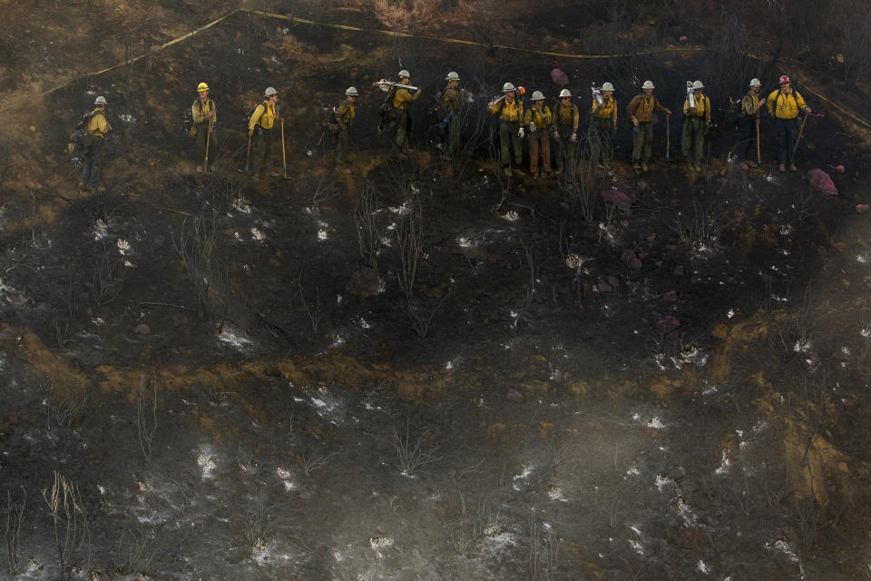 Hand crews line up to work on the remaining hot spots from a brush fire at the Apple Fire in Cherry Valley, Calif., Saturday, Aug. 1, 2020. (AP Photo/Ringo H.W. Chiu)