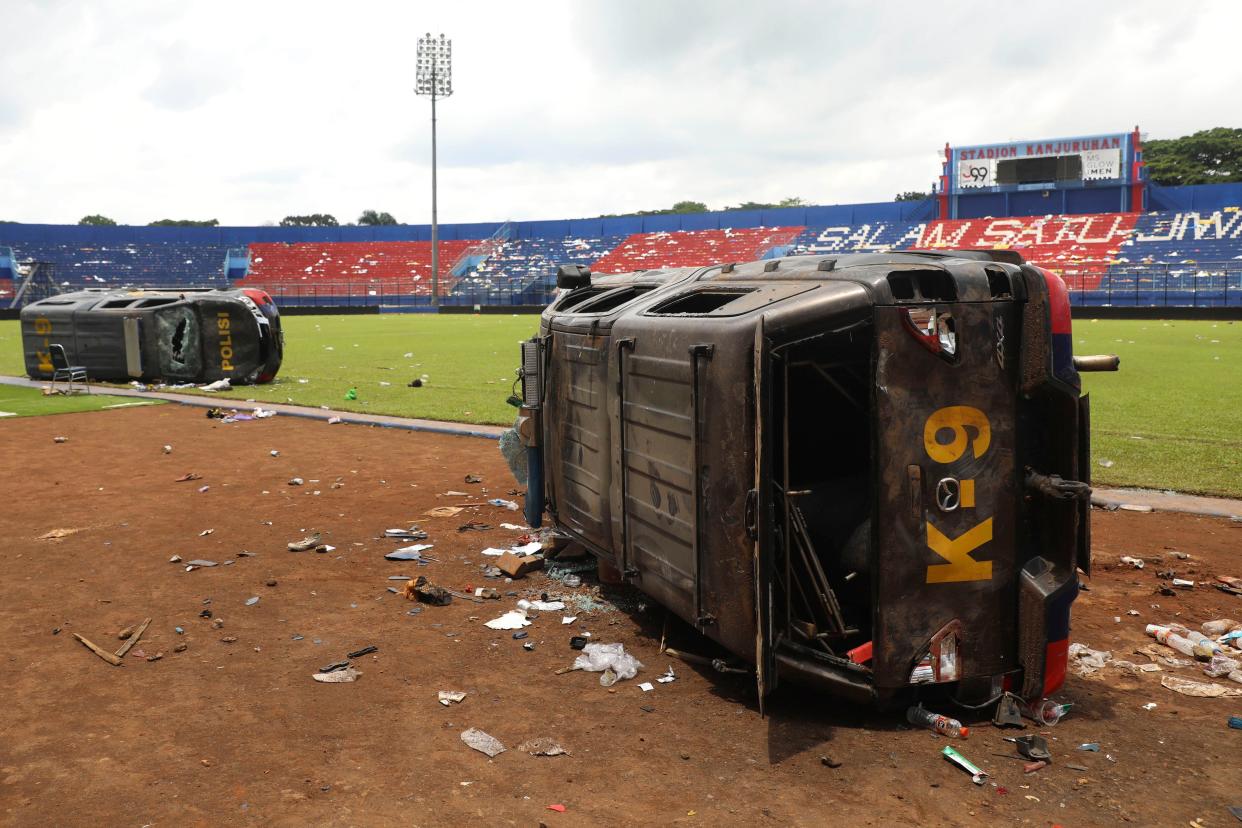 Police cars lie on their side wrecked on the pitch at Kanjuruhan Stadium in Malang, East Java, Indonesia, Sunday, Oct. 2, 2022. Panic at an Indonesian soccer match Saturday left over 100 people dead, most of whom were trampled to death after police fired tear gas to prevent violence. (AP Photo/Trisnadi)