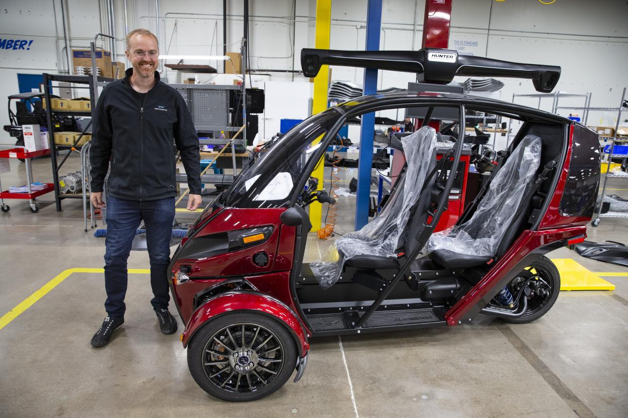 Founder Mark Frohnmayer stands next to Arcimoto’s first production three-wheel electric vehicle that rolled off the line.