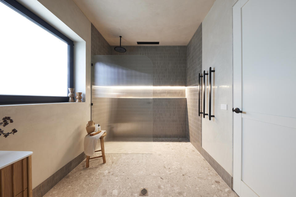 A wide shot of the bathroom, showing the shower on the far wall and the door on the right. 