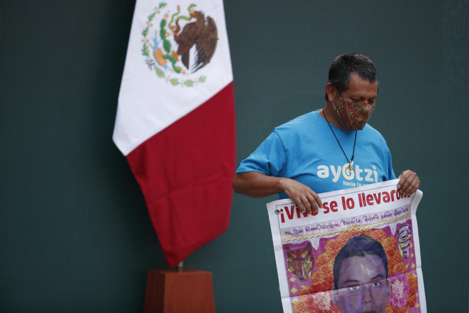 A man holds a poster with an image of one of 43 missing students from the Rural Normal School of Ayotzinapa, during a presentation of the ongoing investigations on the sixth anniversary of the students’ enforced disappearance, at the National Palace in Mexico City, Saturday, Sept. 26, 2020. (AP Photo/Rebecca Blackwell)