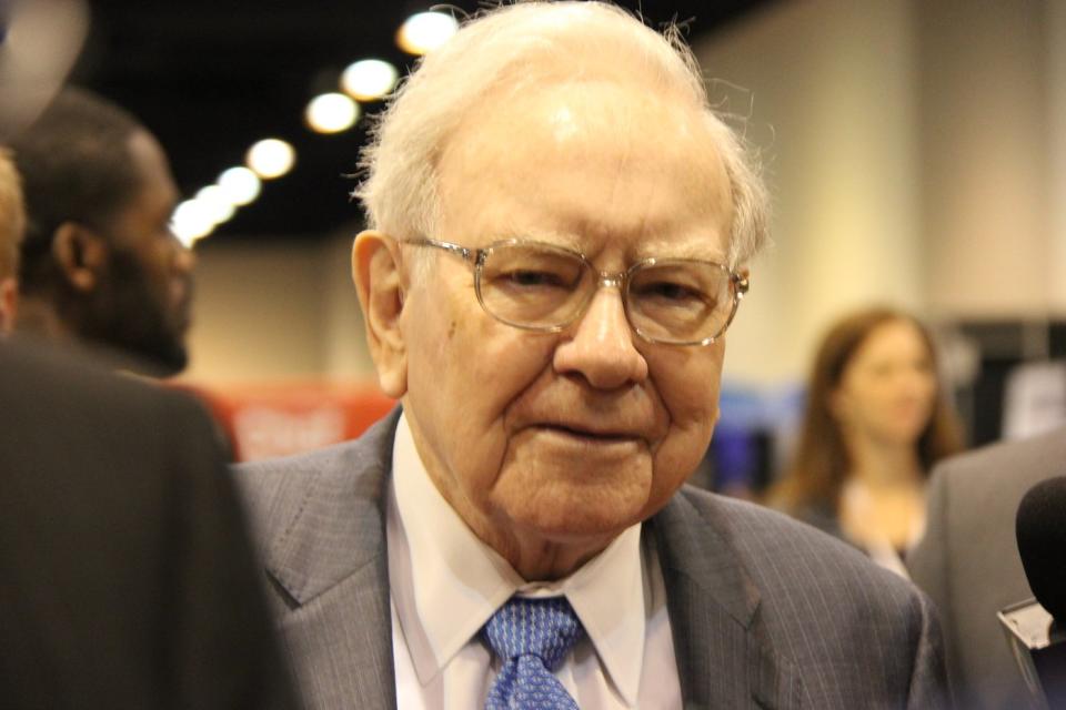 Warren Buffett surrounded by people at Berkshire Hathaway's annual shareholder meeting.