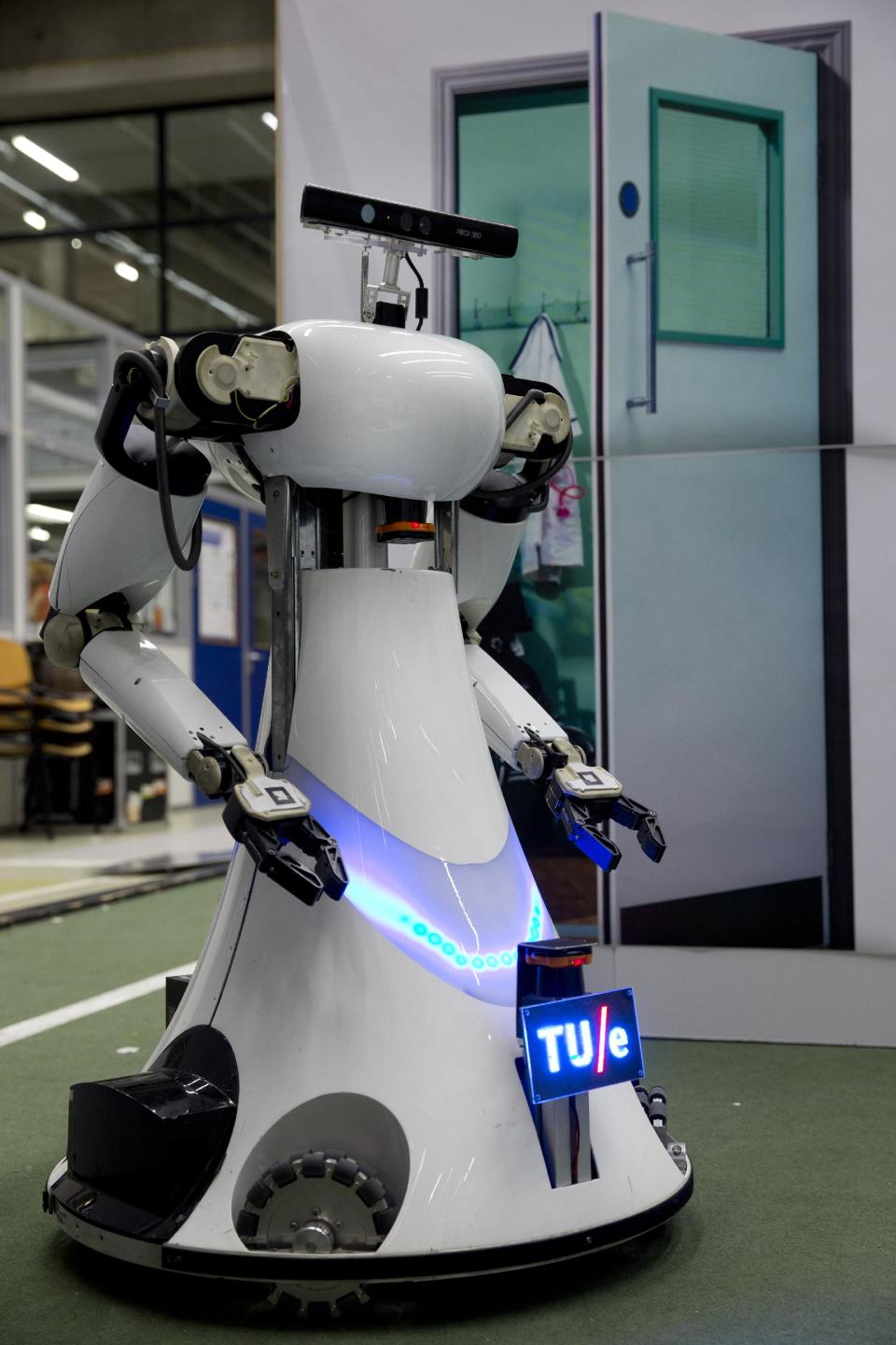 Amigo, a white robot the size of a person, uses information gathered by other robots to move towards a table to pick up a carton of milk and deliver it to an imaginary patient in a mock hospital room at the Technical University of Eindhoven, Netherlands, Wednesday Jan. 15, 2014. A group of five of Europe's top technical universities, together with technology conglomerate Royal Philips NV, are launching an open-source system dubbed "RoboEarth" Thursday. The heart of the mission is to accelerate the development of robots and robotic services via efficient communication with a network, or "cloud". (AP Photo/Peter Dejong)