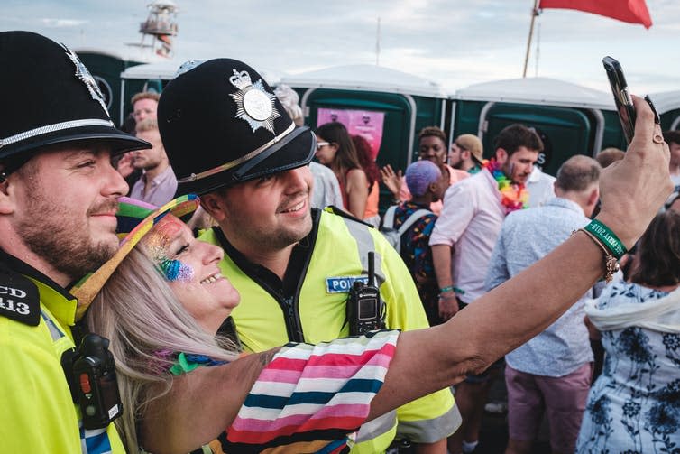 Woman taking a selfie with two police officers.