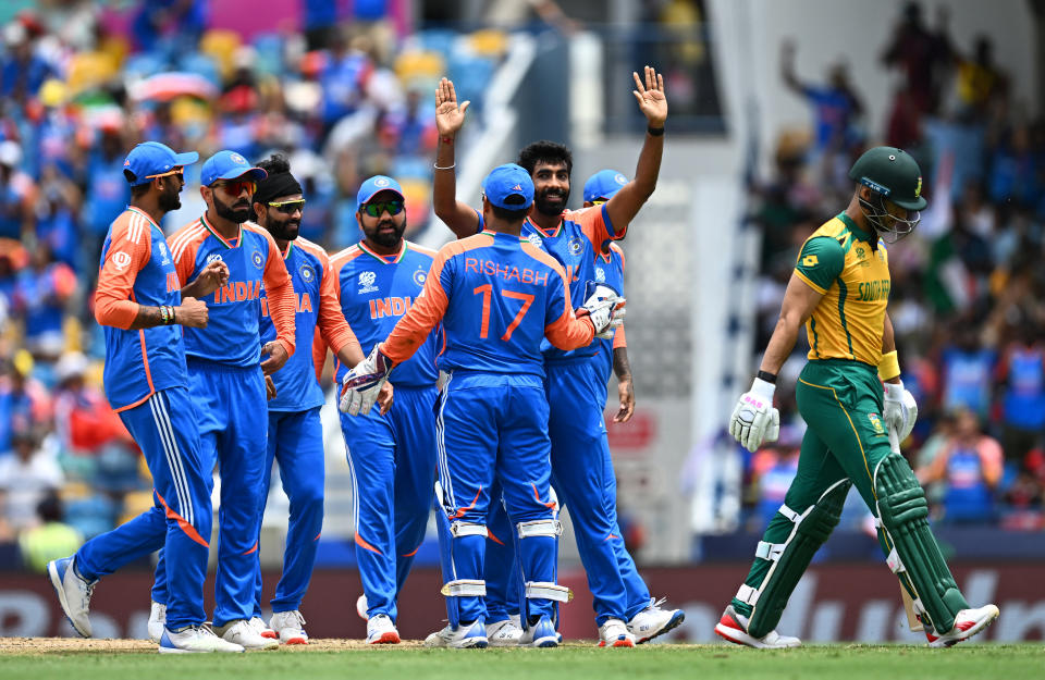 The Indian cricket team celebrates a wicket during a match against South Africa in the Cricket World Cup. A South African player walks away