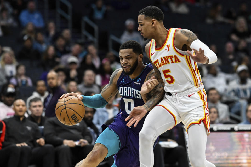 Charlotte Hornets forward Miles Bridges (0) attempts to drive past Atlanta Hawks guard Dejounte Murray (5) during the first half of an NBA basketball game Wednesday, Feb. 14, 2024, in Charlotte, N.C. (AP Photo/Matt Kelley)