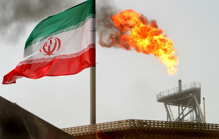 FILE PHOTO: A gas flare on an oil production platform in the Soroush oil fields is seen alongside an Iranian flag in the Gulf July 25, 2005. REUTERS/Raheb Homavandi/File Photo/File Photo