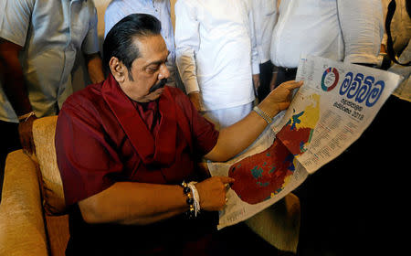 FILE PHOTO - Sri Lanka's former President Mahinda Rajapaksa looks at his victory shown in red on a map in newspaper's article, at the party office after winning the local government election in Colombo, Sri Lanka February 12, 2018. REUTERS/Dinuka Liyanawatte