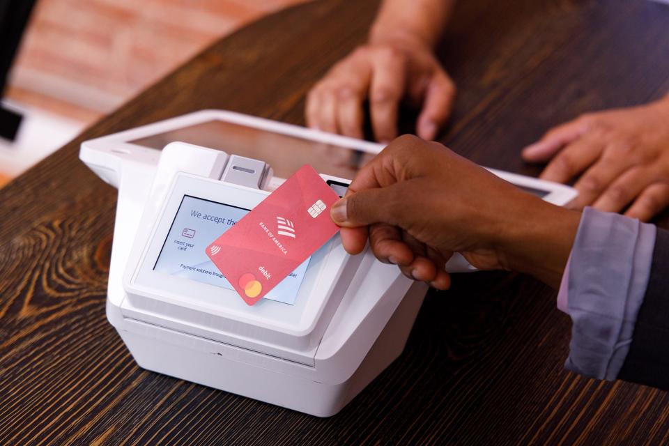 Person making a purchase with debit card by tapping it on the card terminal.