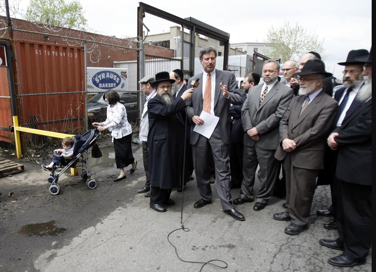 City Council member Bill de Blasio speaks during a press conference with community leaders while a woman with a stroller navigates the undrained sewage at 37th St. between 14th Ave. and 15th Ave. on May 2, 2007 in Brooklyn. The street was, at the time. without a sidewalk or a drainage system, leaving pedestrians to walk amongst the heavy traffic.