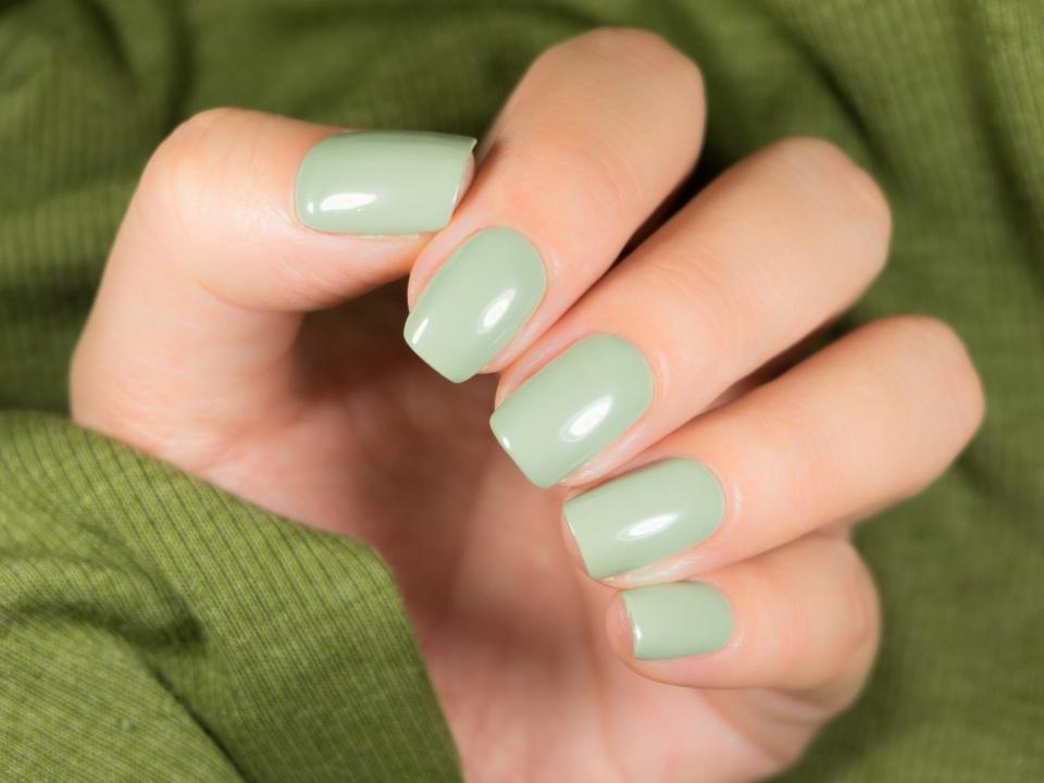 Pastel green manicure on female hand.