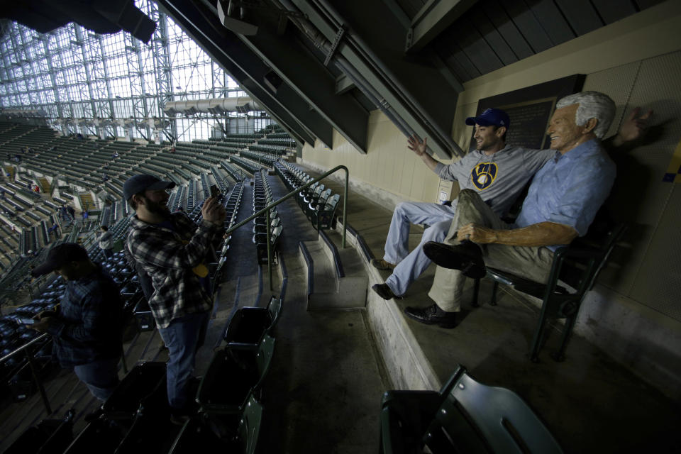 Fans take photos next to a figure of Milwaukee Brewers sportscaster Bob Uecker before Game 1 of the National League Championship Series baseball game between the Milwaukee Brewers and the Los Angeles Dodgers Friday, Oct. 12, 2018, in Milwaukee. (AP Photo/Charlie Riedel)