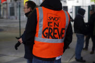 A railway worker wears a vest reading 'On strike » during a meeting at the gare de l'est Railway station, in Paris, Thursday, Dec. 12, 2019. France's prime minister said Wednesday the full retirement age will be increased for the country's youngest, but offered a series of concessions in an ill-fated effort to calm a nationwide protest against pension reforms that critics call an erosion of the country's way of life. (AP Photo/Thibault Camus)