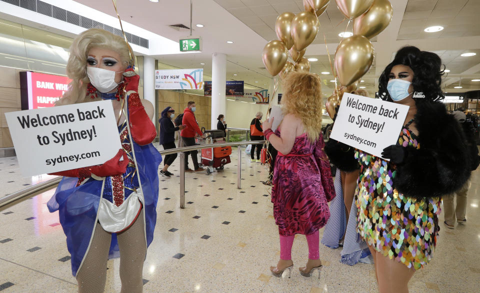 Passengers from New Zealand, at back, are welcomed by drag queens as they arrive at Sydney Airport in Sydney, Australia, Monday, April 19, 2021, as the much-anticipated travel bubble between Australia and New Zealand opens. (AP Photo/Rick Rycroft)