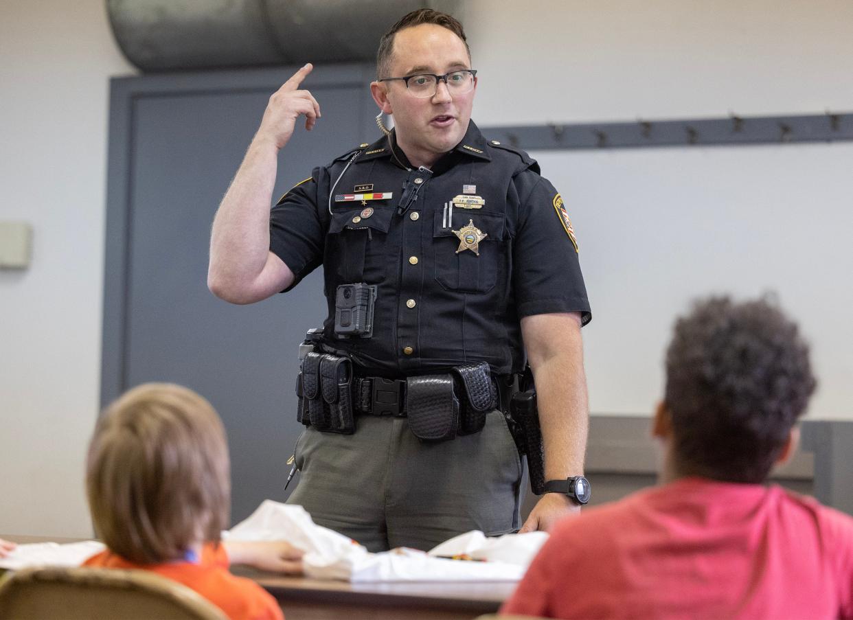 Stark County sheriff's deputy Frank Kuveikis teaches children at the Massillon Boys and Girls Club Safety City about stranger danger and making 911 calls.