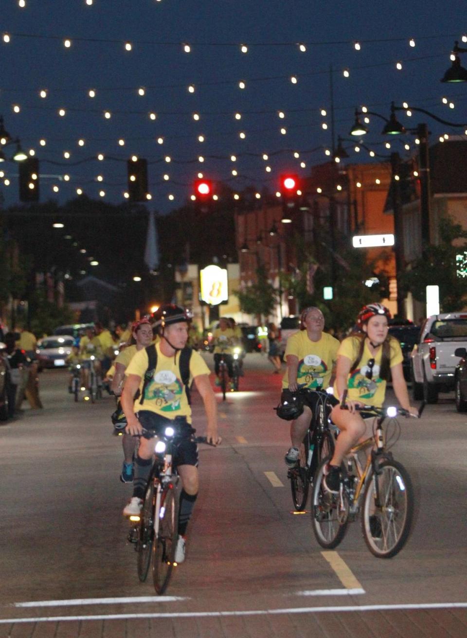 Lights strung across East Main Street provide a festive canopy for the bicyclists.