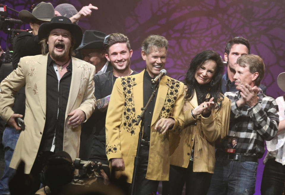 FILE - Travis Tritt, left, Randy Travis, center left, Mary Travis, center right, and Ricky Traywick, right, appear on stage at the "1 Night. 1 Place. 1 Time.: A Heroes and Friends Tribute to Randy Travis" on Feb. 8, 2017 in Nashville, Tenn. (Photo by Laura Roberts/Invision/AP, File)