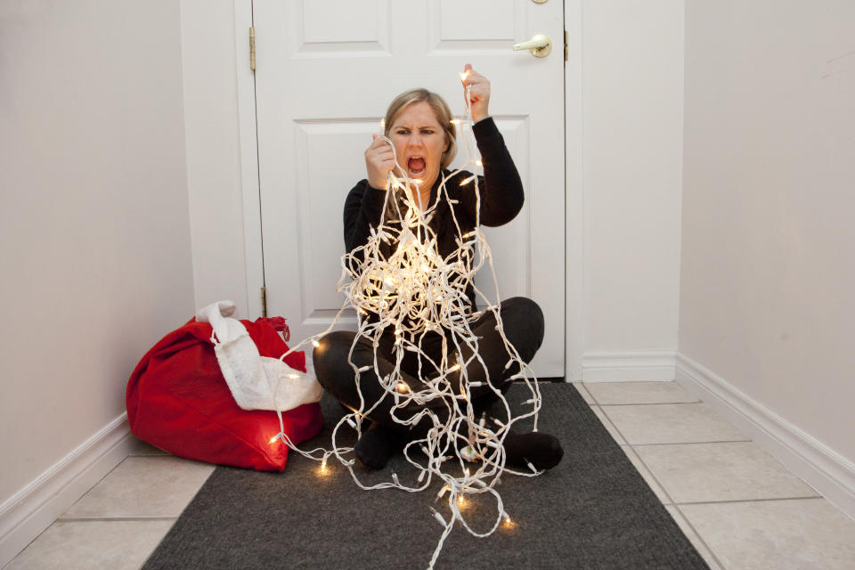 A frustrated woman can't get the christmas lights to untangle so she screams in anger