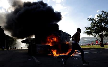 A demonstrator runs near a burning barricade during a protest against President Michel Temer and the latest corruption scandal to hit the country, in Brasilia, Brazil, May 24, 2017. REUTERS/Ueslei Marcelino