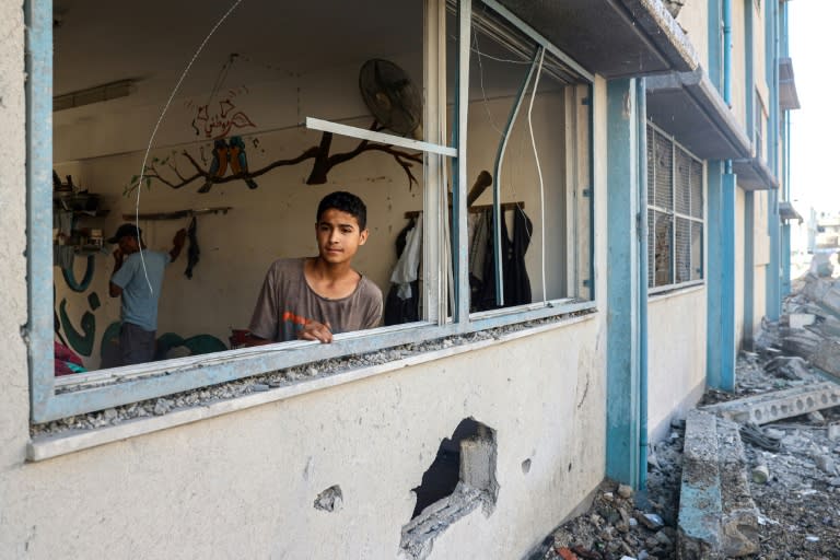A Palestinian boy stands by a shattered window at a UN school sheltering displaced people which was damaged during Israeli bombardment in Khan Yunis, southern Gaza (Eyad BABA)