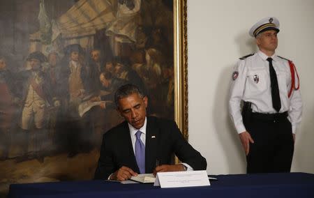 U.S. President Barack Obama signs a condolences book as he pays his respects for victims of the attack at the French newspaper Charlie Hebdo, during a visit to the French Embassy in Washington, January 8, 2015. REUTERS/Jim Bourg