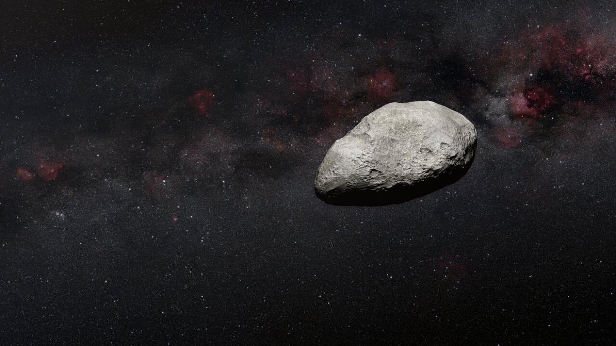  This artist's impression shows a grey, irregularly-shaped asteroid against a dark background. 