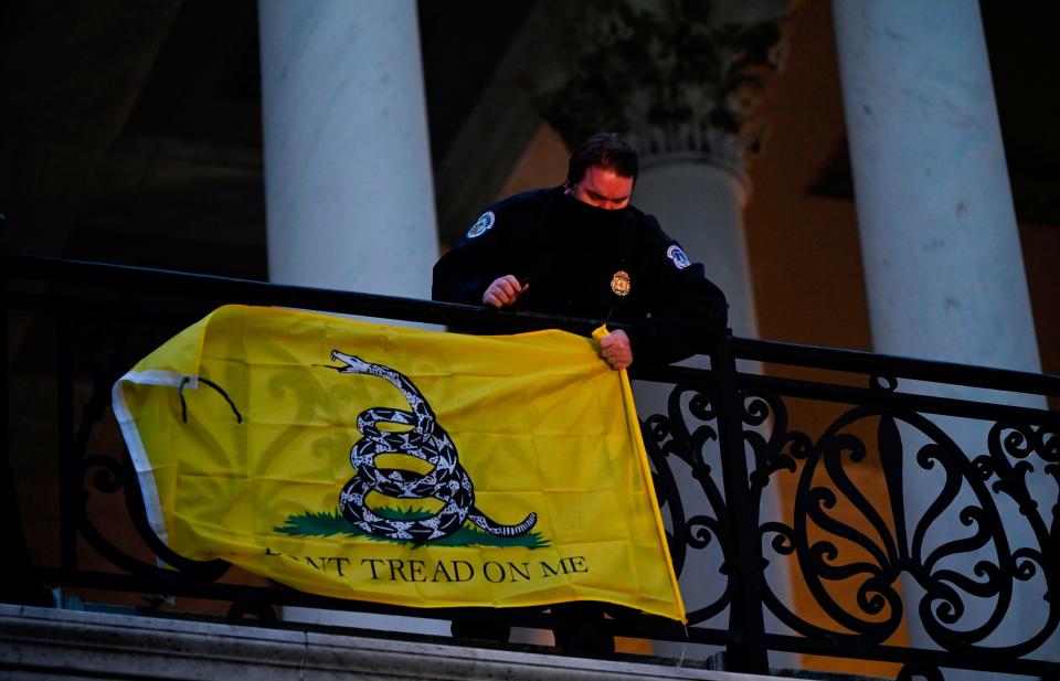 A police officer takes down a flag left hanging by protestors outside of the US Capitol in Washington on Jan. 6, 2021.