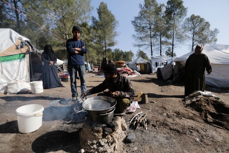 Aziza Hadaja, an internally displaced woman, stands with others outside tents near the town of Afrin