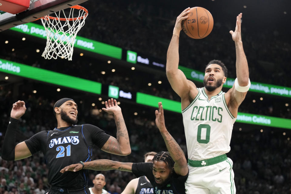 Boston Celtics forward Jayson Tatum, right, drives toward the basket as Dallas Mavericks center Daniel Gafford, left, and forward Derrick Jones Jr., below, defend during the first half of Game 1 of basketball's NBA Finals on Thursday, June 6, 2024, in Boston. (AP Photo/Charles Krupa)