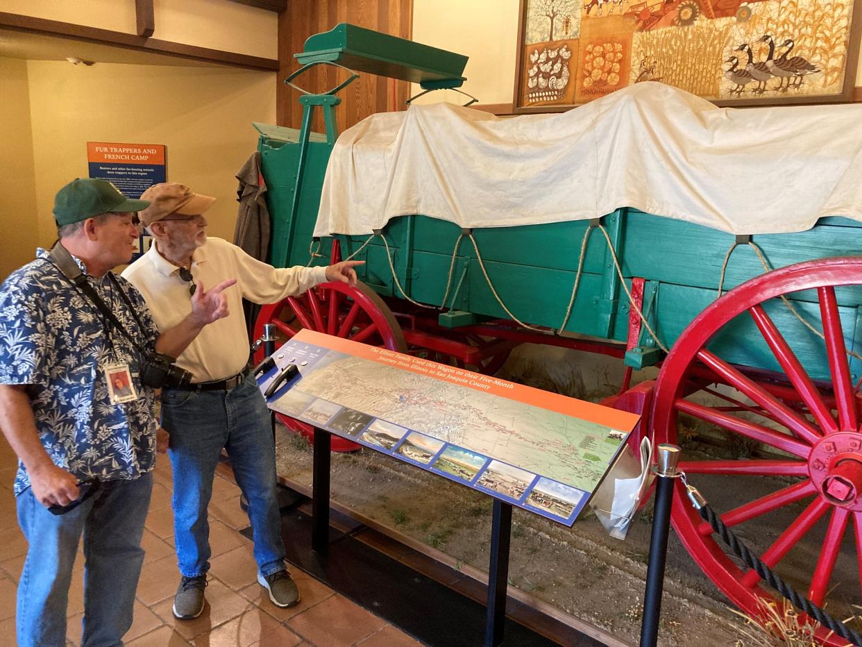 Docent Jack Jacobs offers insight to visitor Gary Pierce on the Elliot Prairie Schooner wagon.