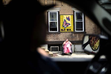 A woman sits on the street in a wheelchair eating a donut in Shamokin May 1, 2014. REUTERS/Mark Makela