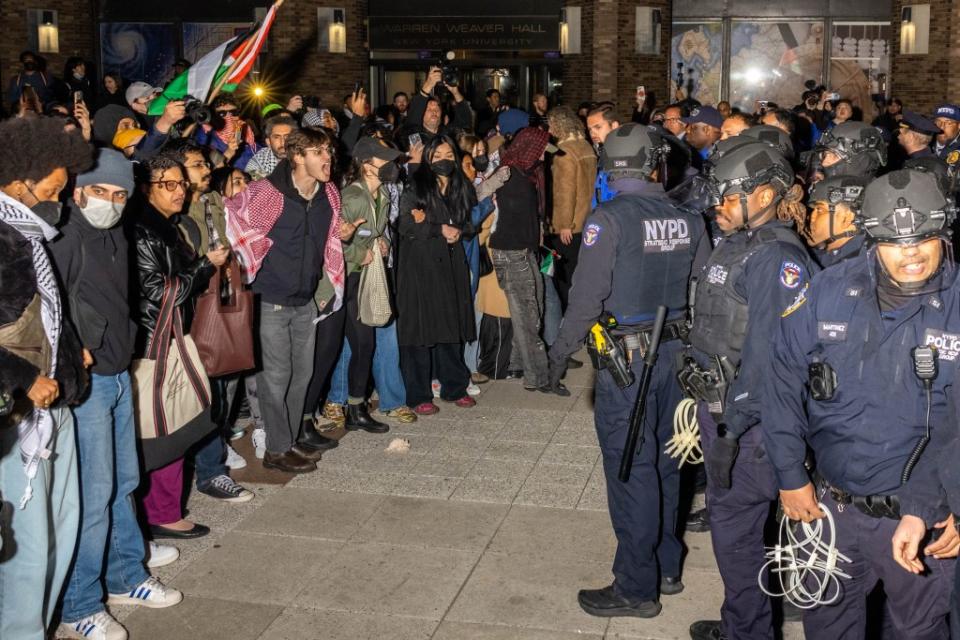 NYPD officers face protesters after detaining demonstrators and clearing an encampment set up by pro-Palestinian students and protesters on NYU’s campus. AFP via Getty Images