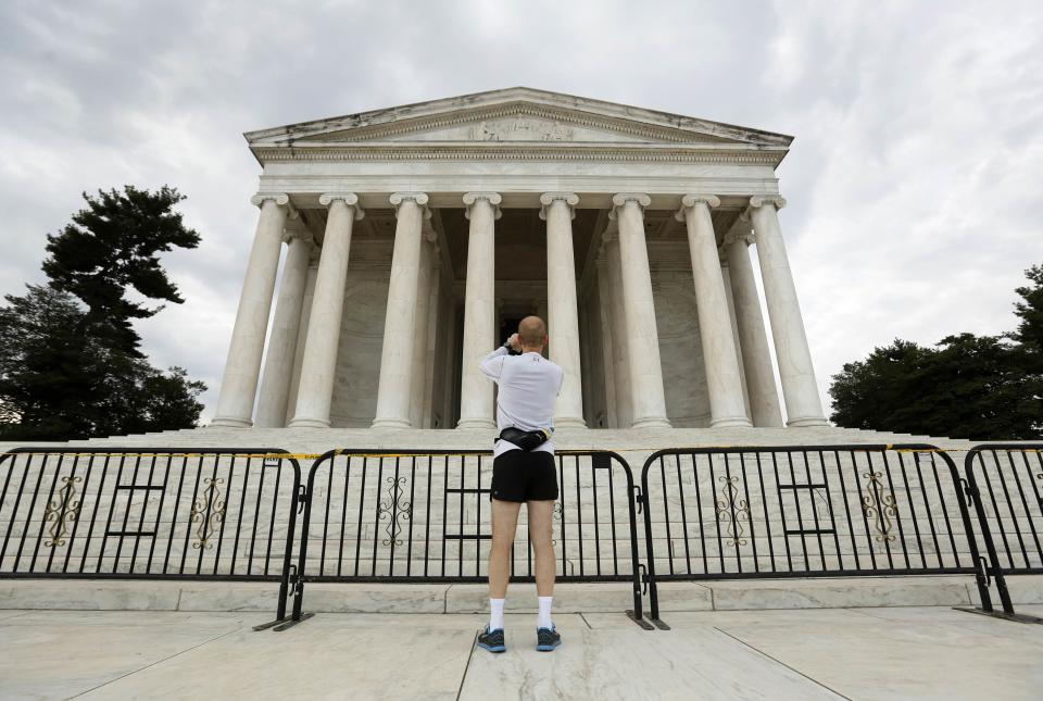 Barricades close off the Jefferson Memorial as a jogger stops to take a photo in Washington October 1, 2013. The U.S. government began a partial shutdown on Tuesday for the first time in 17 years, potentially putting up to 1 million workers on unpaid leave, closing national parks and stalling medical research projects. REUTERS/Kevin Lamarque (UNITED STATES - Tags: POLITICS BUSINESS)