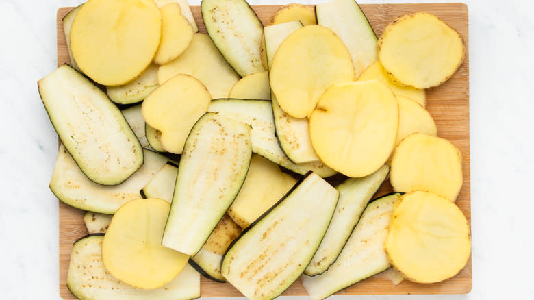 Sliced eggplants and potatoes on chopping board