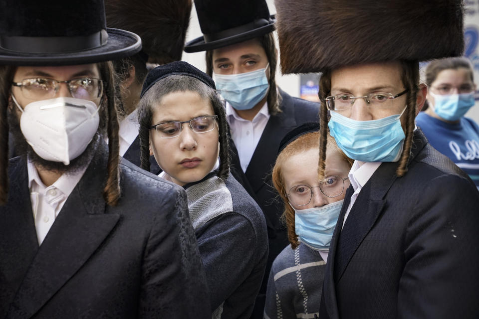 Members of the Orthodox Jewish community gather around a journalist as he conducts an interview on a street corner, Wednesday, Oct. 7, 2020, in the Borough Park neighborhood of the Brooklyn borough of New York. Gov. Andrew Cuomo moved to reinstate restrictions on businesses, houses of worship and schools in and near areas where coronavirus cases are spiking. Many neighborhoods that stand to be affected are home to large enclaves of Orthodox Jews. (AP Photo/John Minchillo)