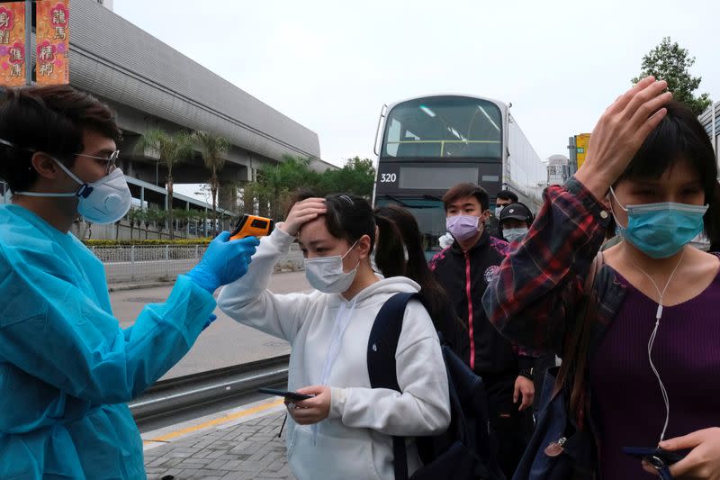 Residents wearing masks and raincoats volunteer to take temperature of passengers following the outbreak of a new coronavirus at a bus stop at Tin Shui Wai, a border town in Hong Kong