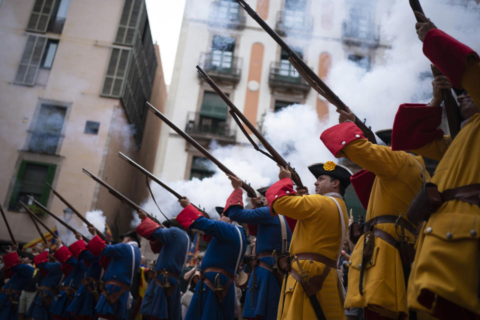 Men dressed in costume shoot their rifles during a performance to celebrate the Catalan National Day in Barcelona, Spain, Sunday, Sept. 11, 2022. Thousands of Spaniards who support the secession of Catalonia are gathering in Barcelona on the region's main holiday. (AP Photo/Joan Mateu Parra)